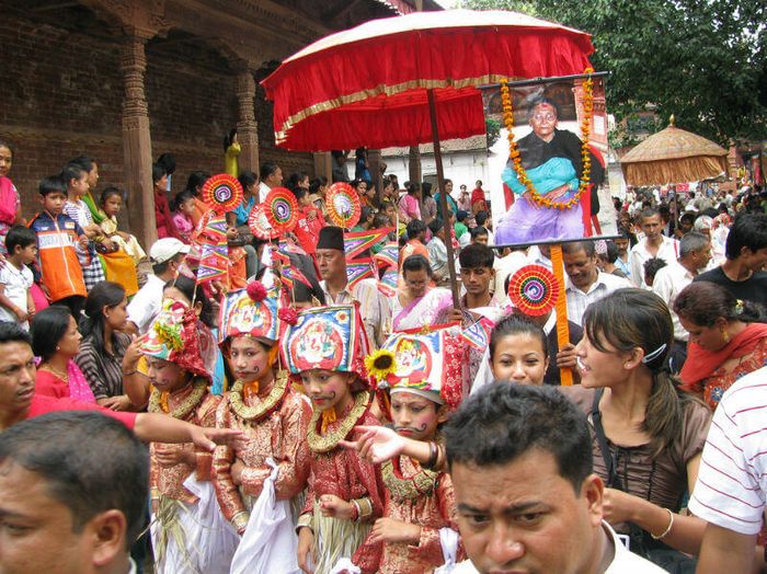 A crowd of people in colourful traditional costume walking through the streets of Kathmandu for Gaijatra