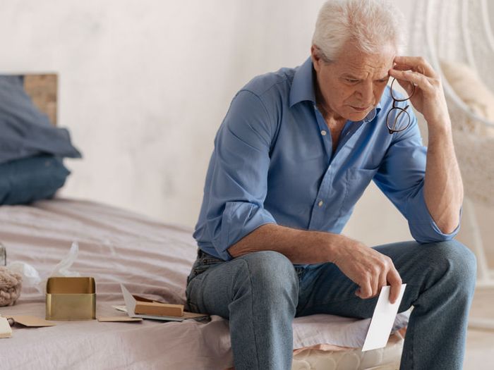A grieving man is caught up in emotion as he looks through old photographs