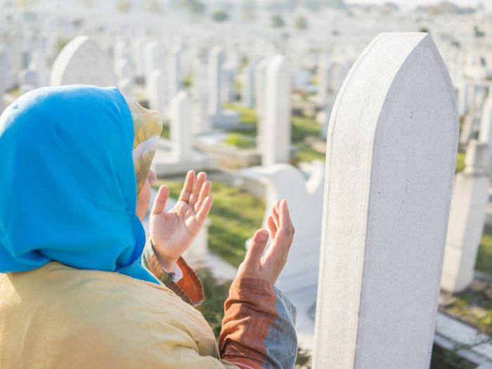 Muslim woman praying at an Islamic cemetery