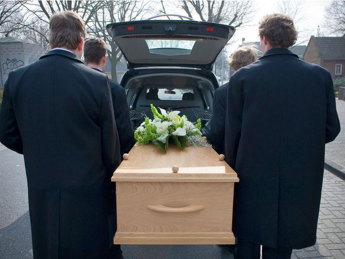 Pallbearers carrying a coffin to the hearse for a funeral service