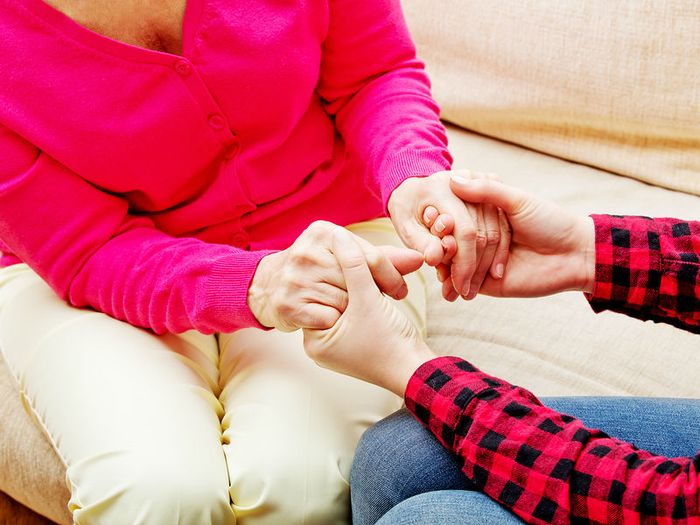 A daughter clasps her mother's hand