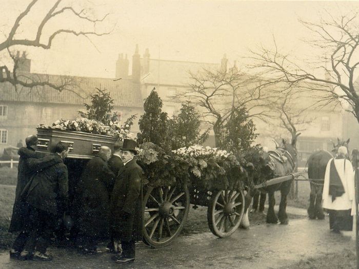 Horse drawn hearse with pallbearers and funeral directors