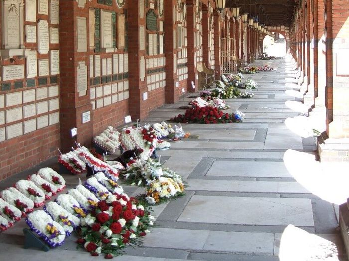 Floral displays in cloister outside Golders Green Crematorium, with memorial plaques on the wall