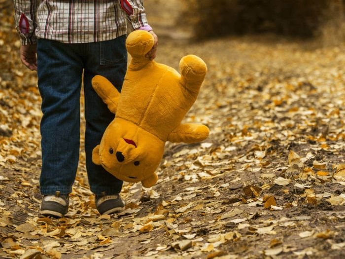 Grieving child carrying a teddy bear