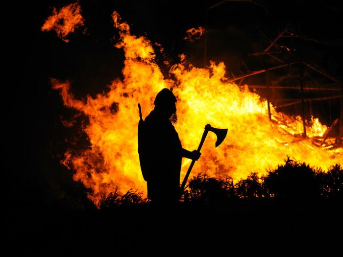 A viking warrior is silhouetted by a flaming funeral pyre