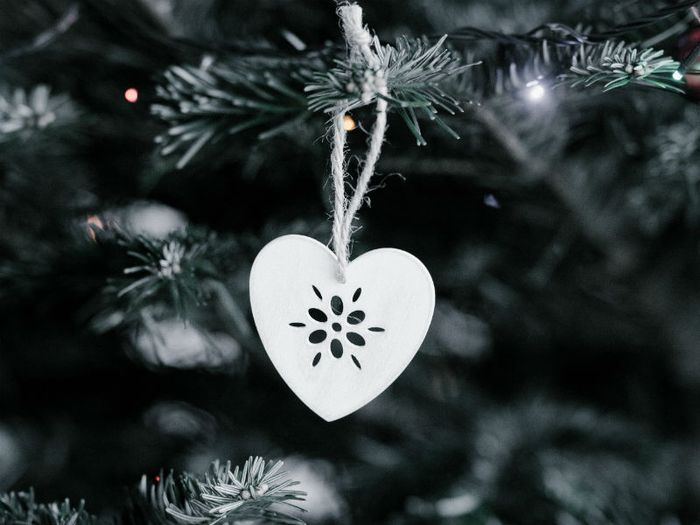 Close-up of a white heart shaped direction hanging on a Christmas tree