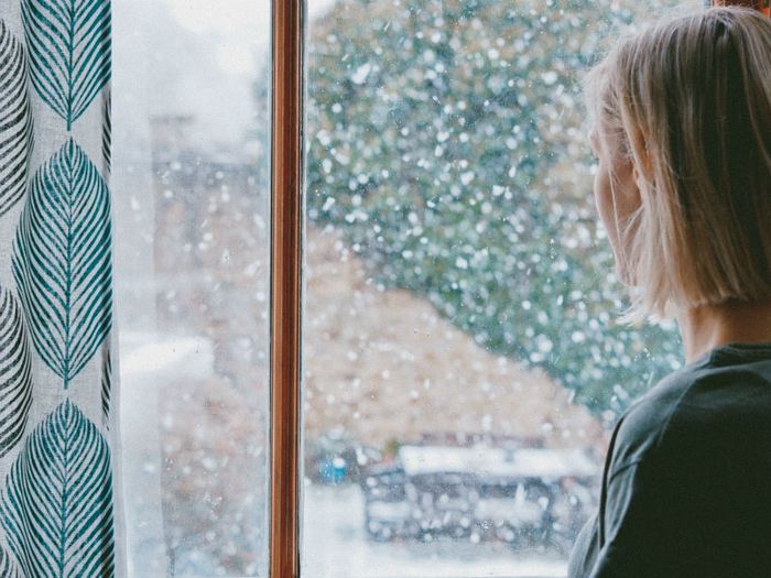 a woman looks out of a rainy window