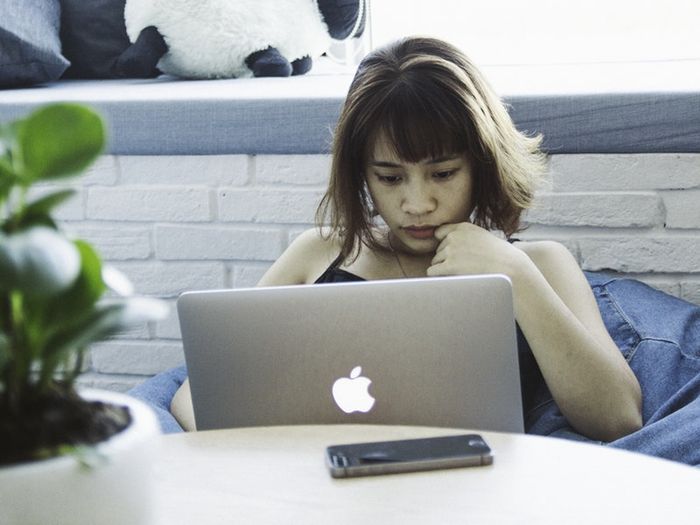 A pensive woman writing on her laptop