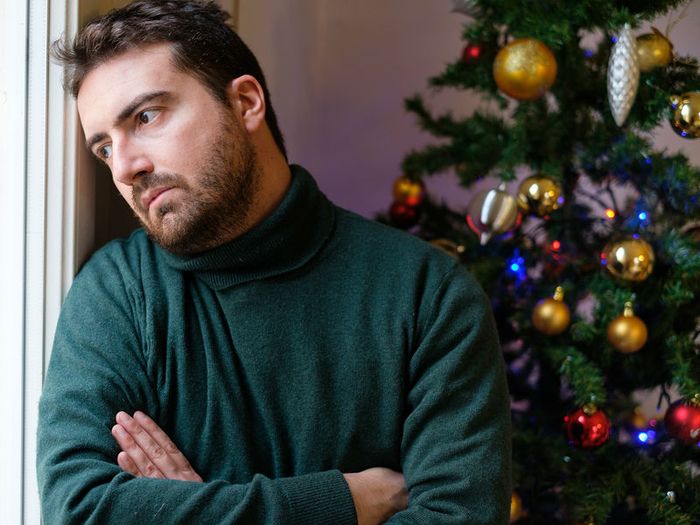 A bereaved man takes in sad news, in a room decorated for Christmas